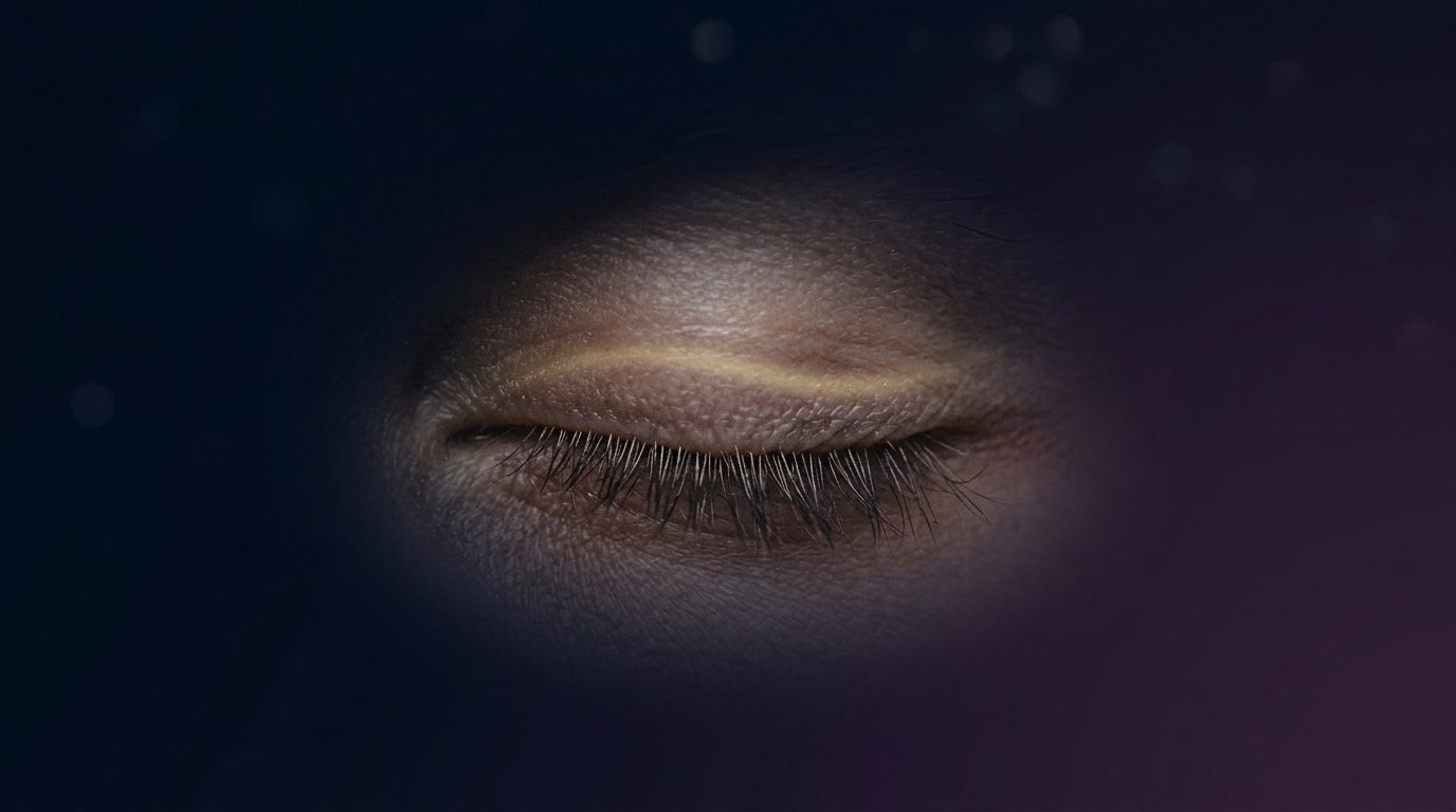 Closed eye in macro with pale gold light moving across the eyelid