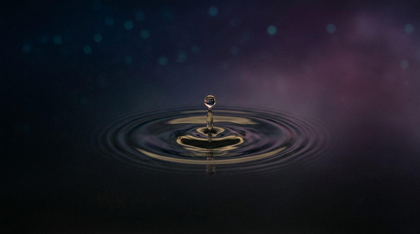 Single drop landing on still dark water creating concentric pale-gold ripples